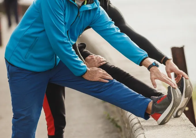 Physiotherapist supporting a patient through a guided knee and hamstring stretch