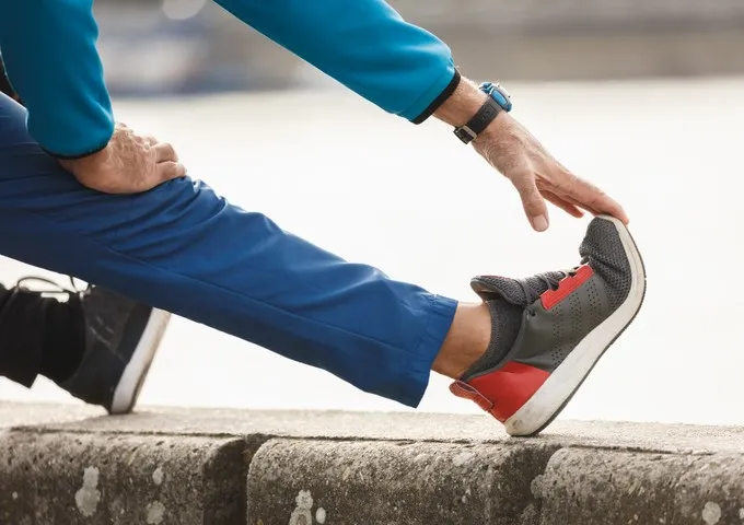 Person performing a guided lower limb and back mobility stretch outdoors