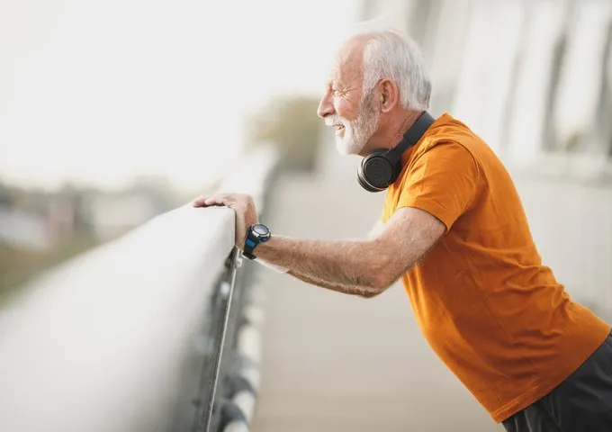 Man stretching his shoulder against a railing during rehabilitation